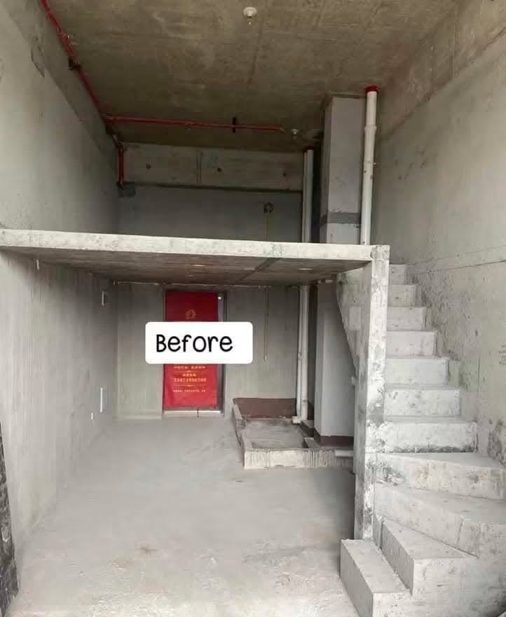 The unit before work started: a bare concrete shell with an unfinished mezzanine slab and rough concrete stairs