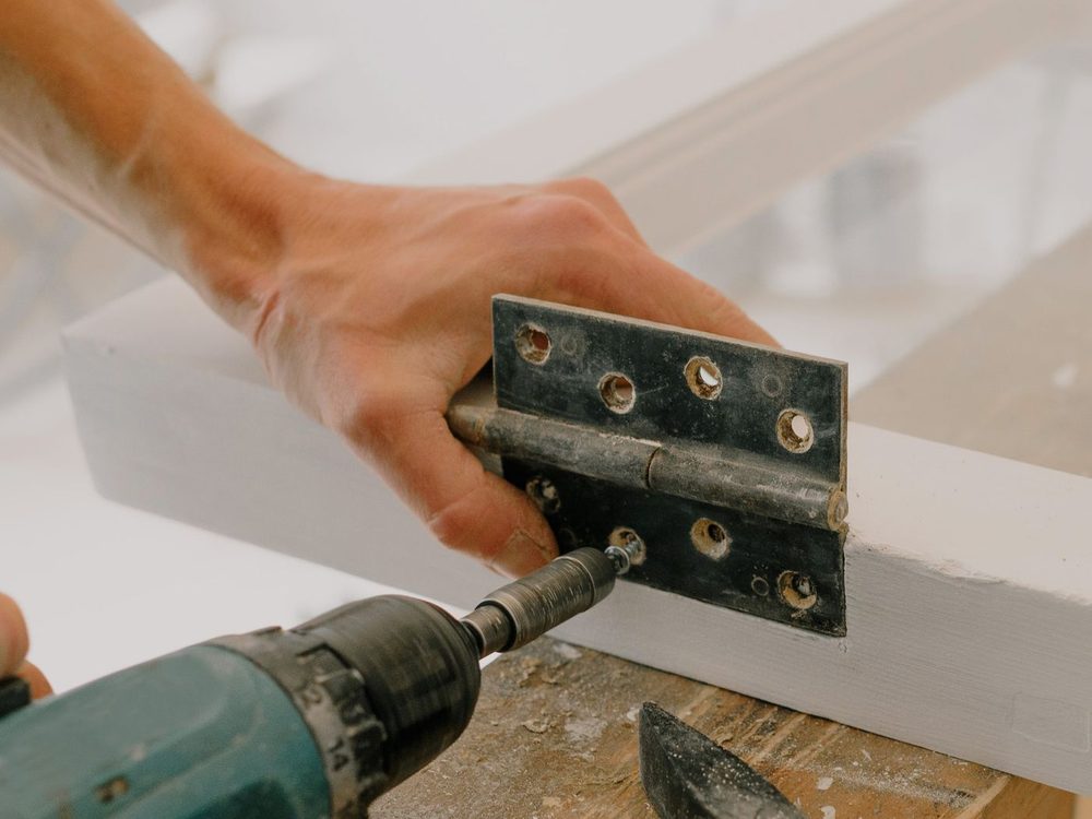 A craftsman fixing ironmongery to a timber frame during renovation work